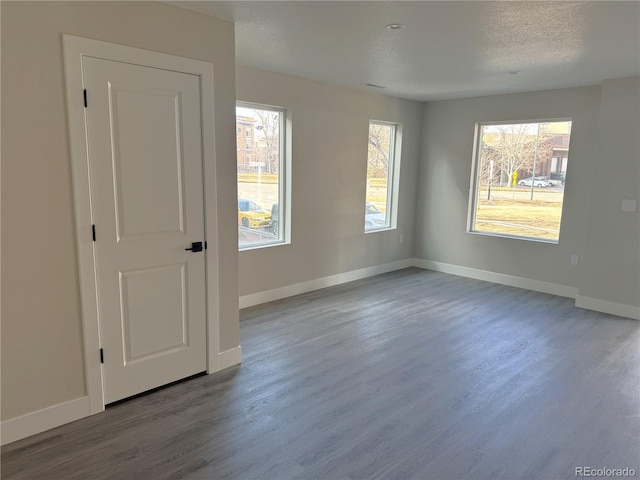 unfurnished room featuring a textured ceiling, baseboards, and wood finished floors