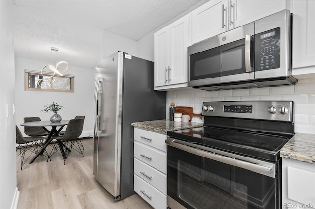 kitchen featuring appliances with stainless steel finishes, white cabinetry, light wood-style flooring, and a textured ceiling