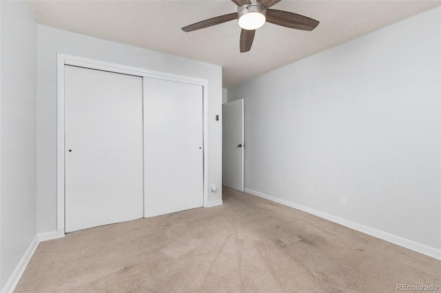 unfurnished bedroom with baseboards, ceiling fan, a textured ceiling, carpet flooring, and a closet