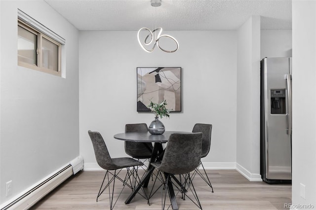 dining space featuring a textured ceiling, baseboard heating, light wood-type flooring, and a notable chandelier