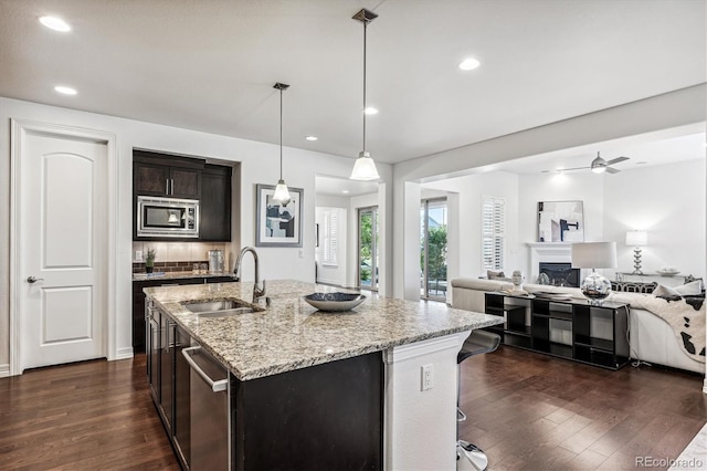 kitchen featuring appliances with stainless steel finishes, ceiling fan, sink, pendant lighting, and an island with sink