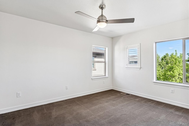 spare room featuring dark carpet and ceiling fan