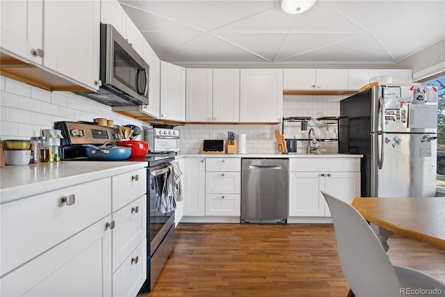 kitchen with sink, appliances with stainless steel finishes, dark hardwood / wood-style flooring, white cabinets, and backsplash