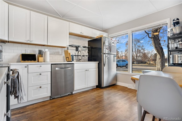 kitchen with dark hardwood / wood-style flooring, backsplash, white cabinets, and appliances with stainless steel finishes