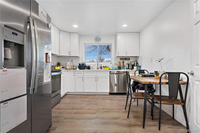 kitchen featuring stainless steel appliances, white cabinetry, sink, and light hardwood / wood-style flooring