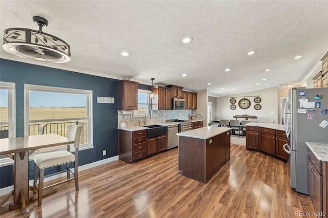 39245 Big Springs Rd, Rush, CO 80833 - kitchen with stainless steel appliances, dark wood-style flooring, a kitchen island, a sink, and ornamental molding