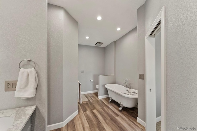 39245 Big Springs Rd, Rush, CO 80833 - bathroom with a freestanding tub, wood finished floors, visible vents, vanity, and baseboards