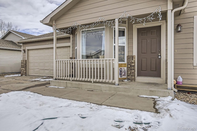 snow covered property entrance with a garage