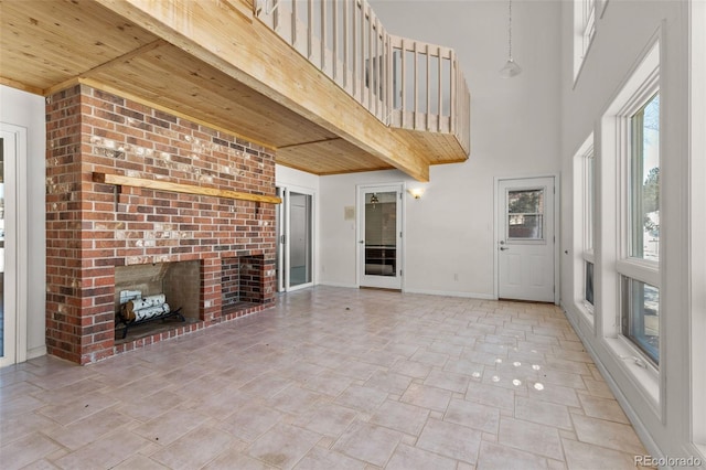 unfurnished living room featuring a brick fireplace, wood ceiling, and a high ceiling