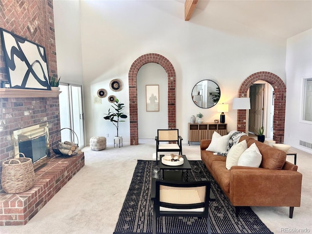 carpeted living room with a brick fireplace, beam ceiling, and high vaulted ceiling