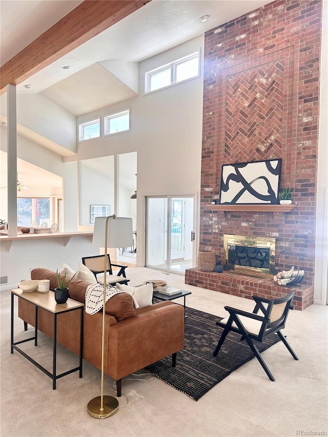 carpeted living room with beam ceiling, a wealth of natural light, a brick fireplace, and a high ceiling