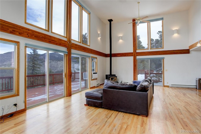 living room with a healthy amount of sunlight, a high ceiling, and a wood stove