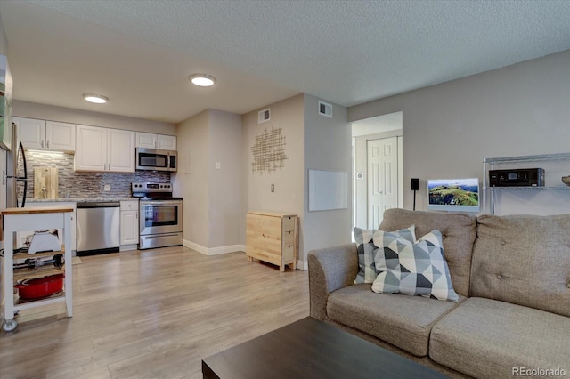 living room with a textured ceiling and light hardwood / wood-style flooring