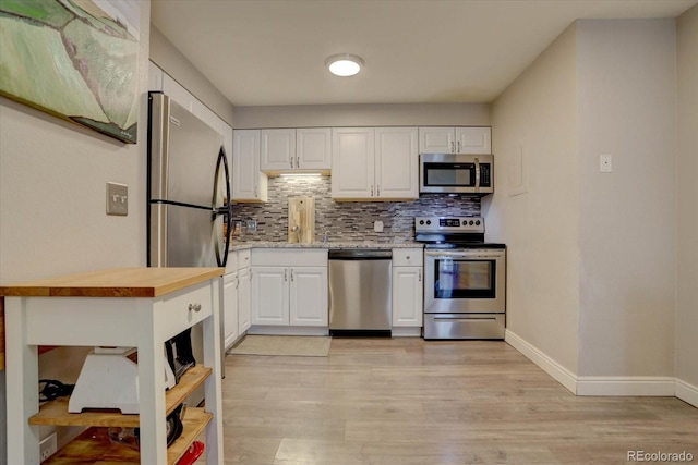 kitchen with light wood-type flooring, stainless steel appliances, white cabinetry, and butcher block countertops