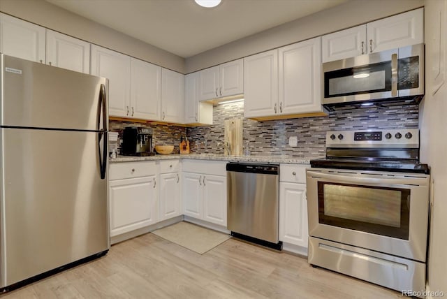 kitchen with light stone countertops, appliances with stainless steel finishes, light hardwood / wood-style flooring, and white cabinetry