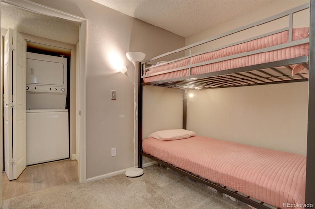 unfurnished bedroom featuring light hardwood / wood-style floors, stacked washing maching and dryer, and a textured ceiling