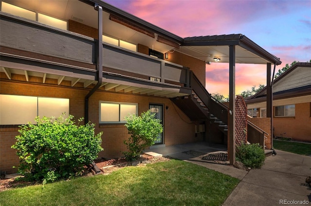 12820 Willow Ln Unit 9, Golden, CO 80401 - back of property at dusk featuring brick siding, stairway, a yard, and a patio area