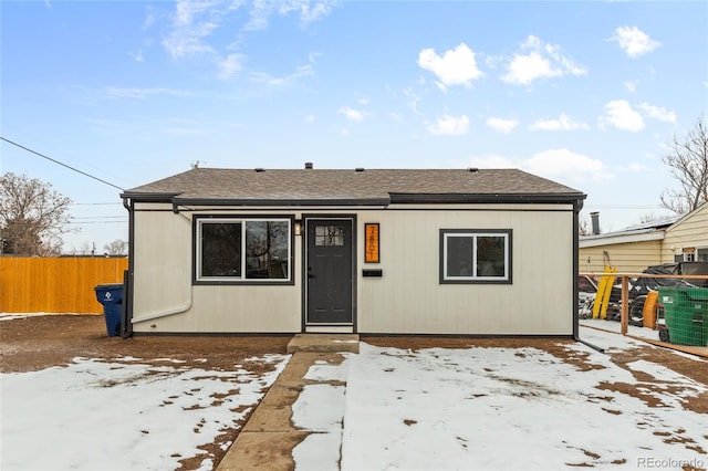 view of front facade with roof with shingles, cooling unit, and fence