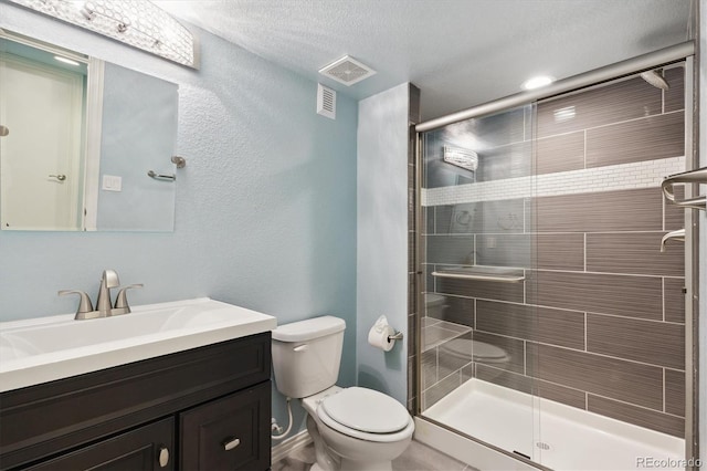 bathroom with vanity, a shower with shower door, a textured ceiling, and toilet