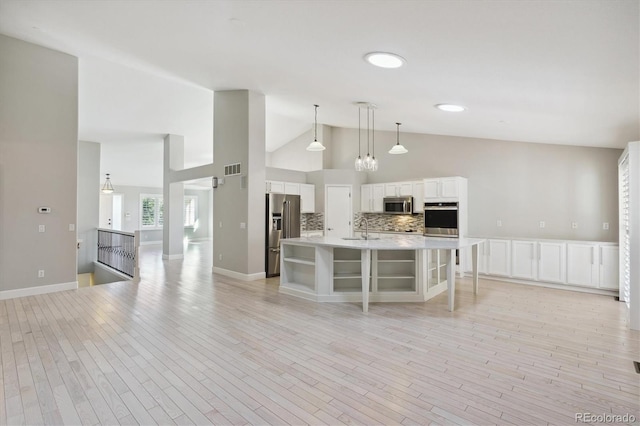 kitchen with light hardwood / wood-style flooring, stainless steel appliances, a center island with sink, sink, and white cabinets