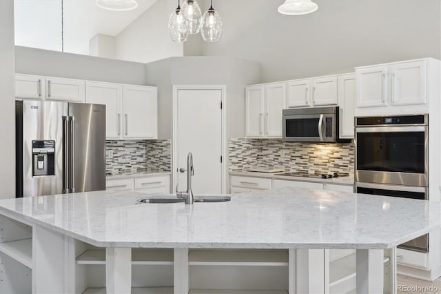 kitchen featuring white cabinets, hanging light fixtures, an island with sink, sink, and stainless steel appliances