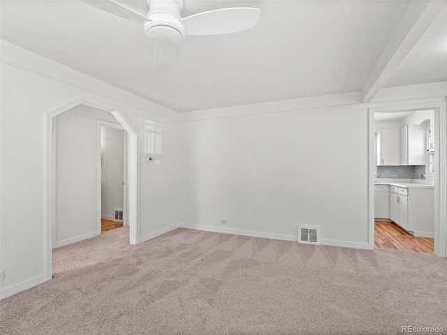 spare room featuring light carpet, ceiling fan, visible vents, and baseboards