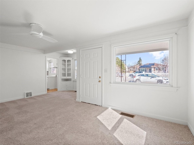 unfurnished room featuring baseboards, visible vents, ceiling fan, and carpet flooring