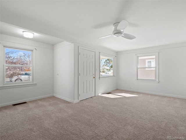 carpeted spare room featuring baseboards, visible vents, and a ceiling fan