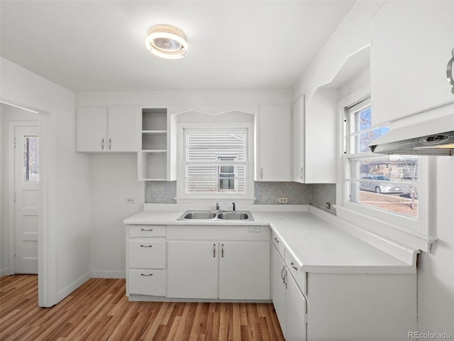 kitchen featuring a sink, light countertops, light wood-style floors, white cabinetry, and backsplash