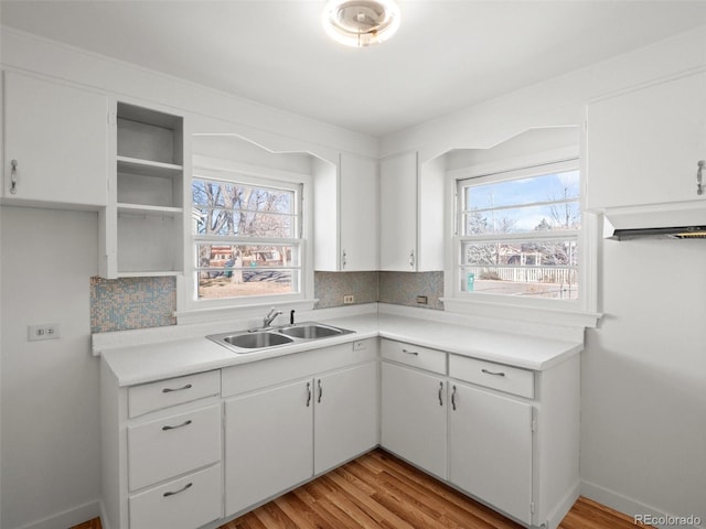 kitchen with a healthy amount of sunlight, decorative backsplash, a sink, and light countertops