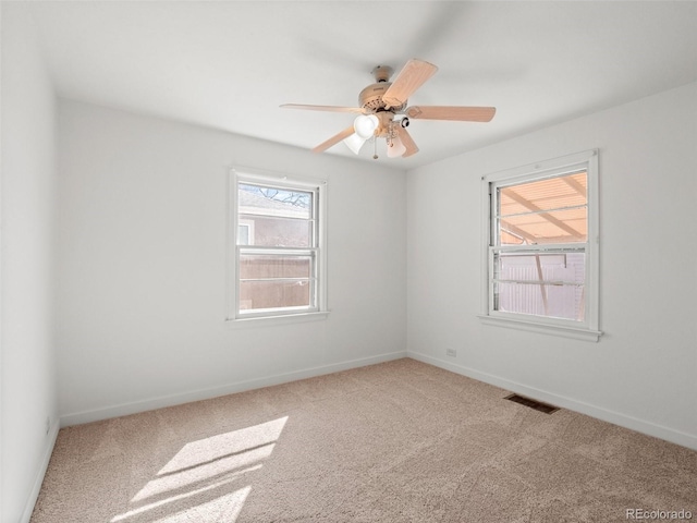 carpeted empty room featuring a ceiling fan, visible vents, and baseboards