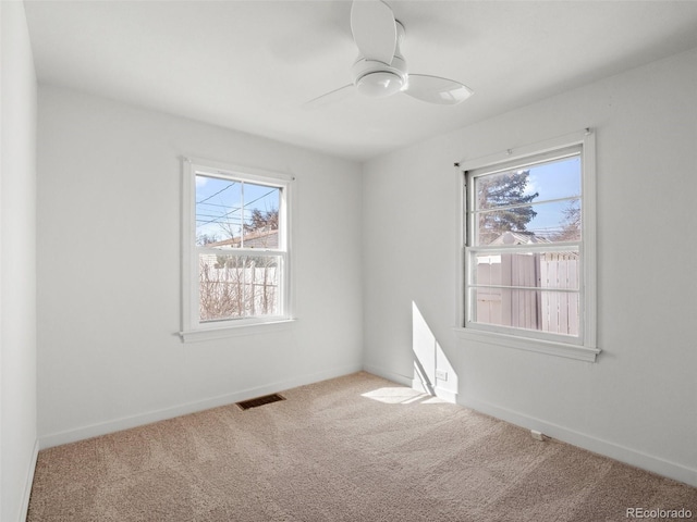 unfurnished room with carpet floors, visible vents, ceiling fan, and baseboards