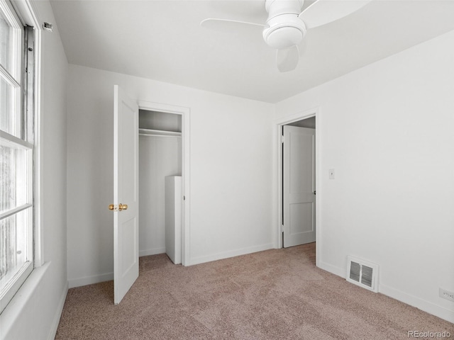 unfurnished bedroom featuring carpet flooring, visible vents, baseboards, a ceiling fan, and a closet