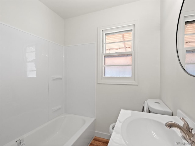 full bathroom with baseboards, a sink, toilet, and wood finished floors