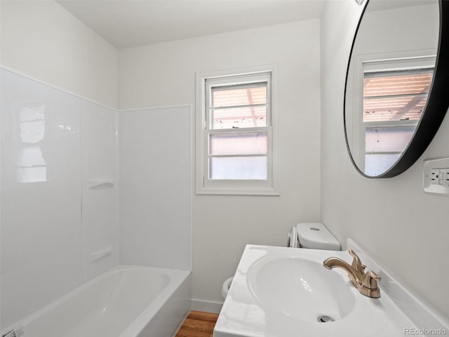 full bath with toilet, a sink, and wood finished floors