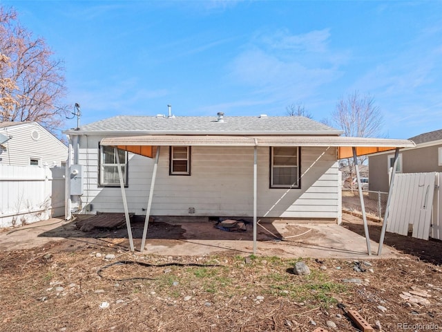 back of property with a shingled roof and fence