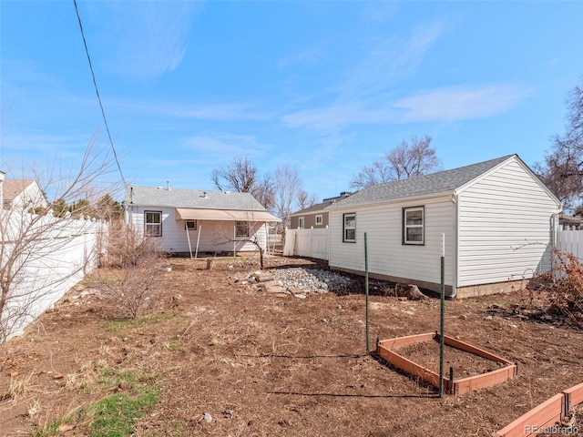 rear view of house featuring a fenced backyard, a vegetable garden, and an outdoor structure