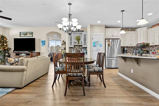 dining room featuring ceiling fan with notable chandelier and light wood-type flooring