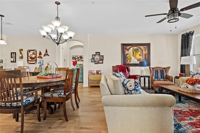 dining space with ceiling fan with notable chandelier and light hardwood / wood-style flooring