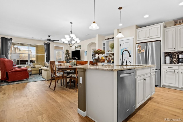 kitchen featuring white cabinetry, light wood-type flooring, an island with sink, and pendant lighting