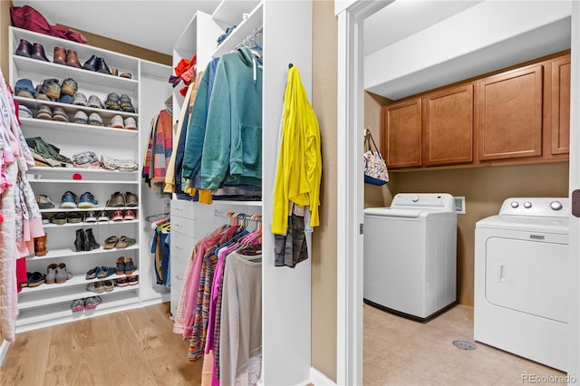 clothes washing area featuring cabinets, separate washer and dryer, and light hardwood / wood-style flooring