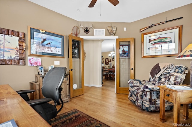 office featuring ceiling fan with notable chandelier and light hardwood / wood-style flooring