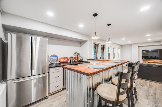 22428 Quail Run Ln, Parker, CO 80138 - kitchen with freestanding refrigerator, wood counters, light wood-style floors, a kitchen breakfast bar, and white cabinets