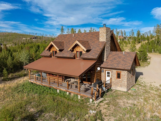 back of house featuring stone siding and a chimney