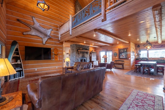 living room with a healthy amount of sunlight, a stone fireplace, wooden walls, and hardwood / wood-style flooring