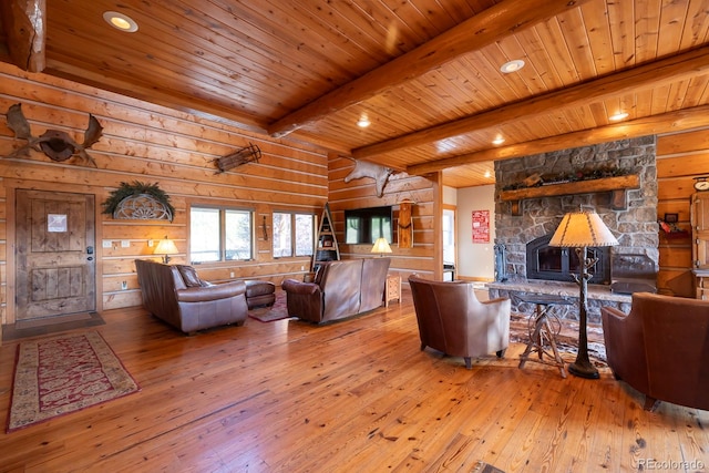 living room with wood walls, hardwood / wood-style flooring, beam ceiling, and a stone fireplace