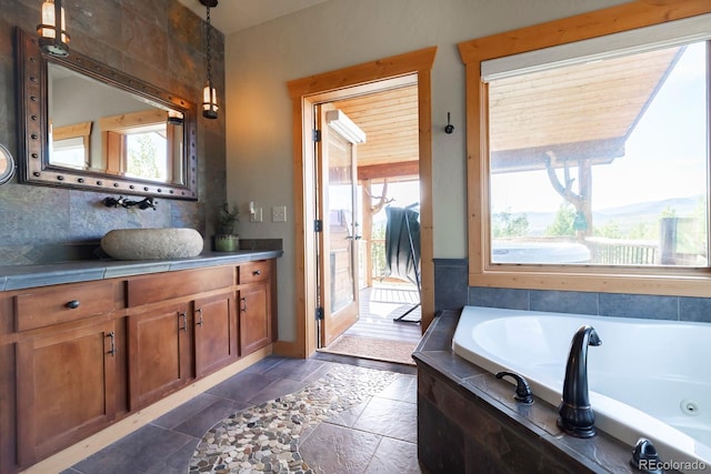 bathroom with tiled tub and vanity