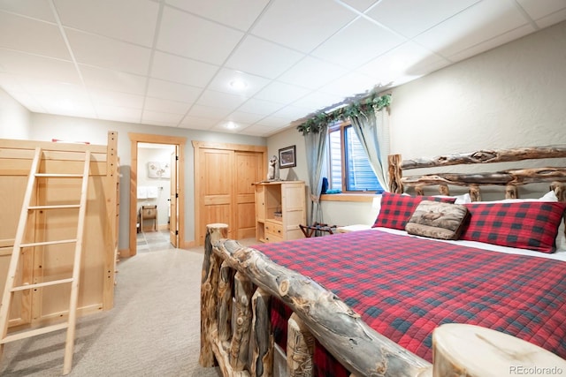 carpeted bedroom with a closet and a paneled ceiling