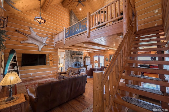 staircase with hardwood / wood-style floors, a stone fireplace, wood ceiling, high vaulted ceiling, and ceiling fan