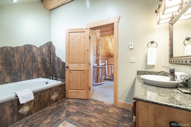 full bath with a textured wall, vanity, and a bath